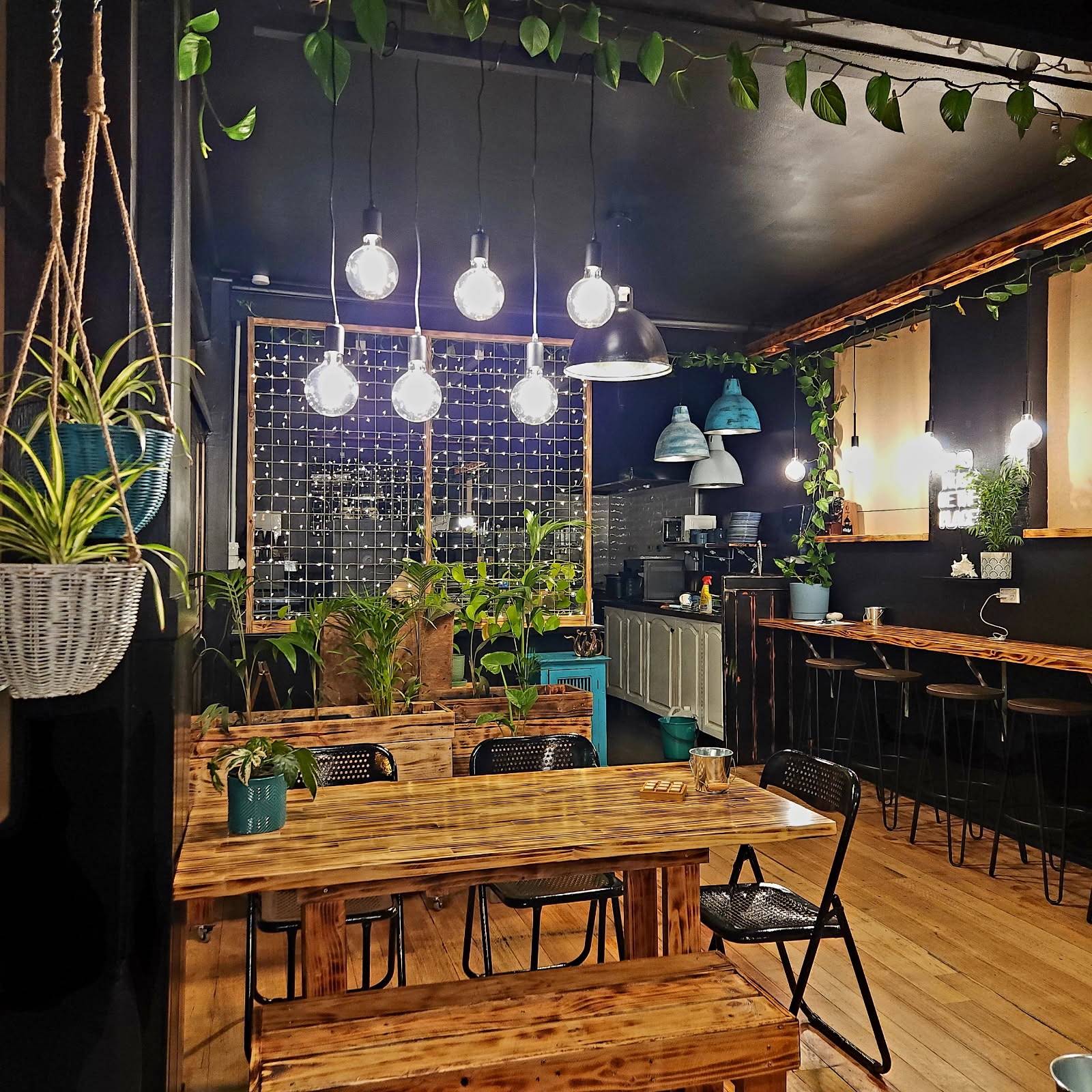 Inside Sailor Restaurant in Deloraine, with raw-timber tables, black walls, hanging lights and greenery